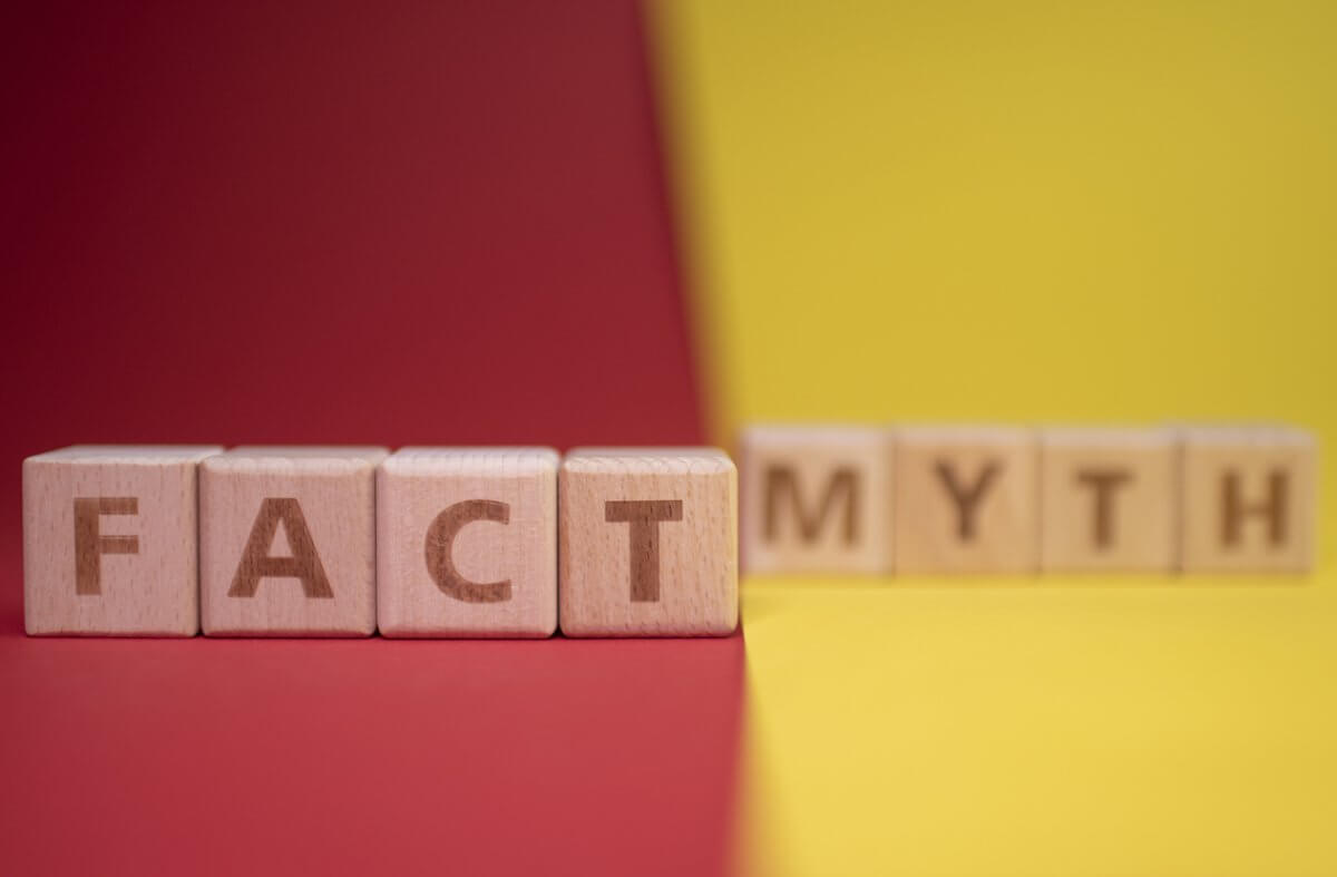 Photograph of wooden blocks with words on them that say "fact" and "myth" in front of a red and yellow background.