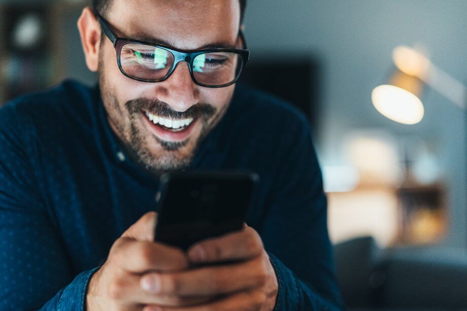 smiling man texting on cell phone