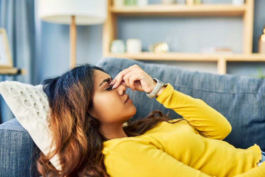 woman laying on couch with headache