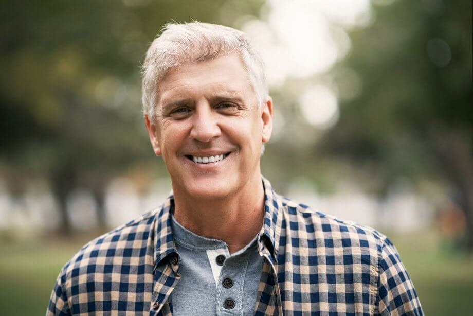 older man standing outside, smiling