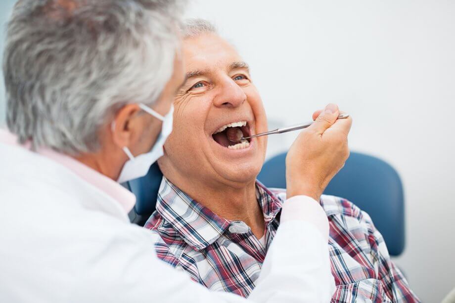 dentist using dental mirror to look in patient's mouth