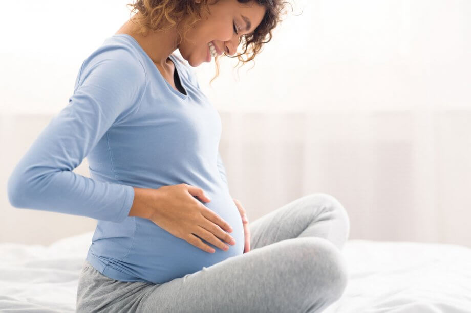 pregnant woman sitting, holding belly