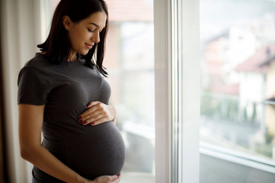 pregnant woman standing by window