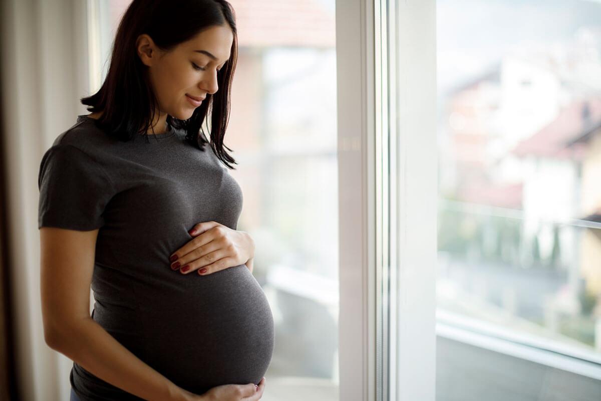 pregnant woman standing by window