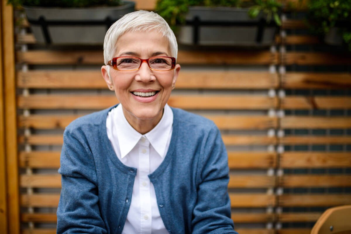 older woman sitting outside, smiling