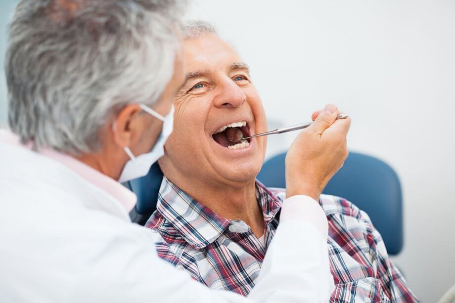 dentist using dental mirror to look in patient's mouth