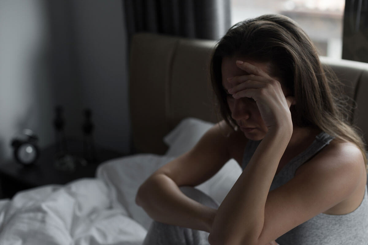 woman sitting up in bed holding head