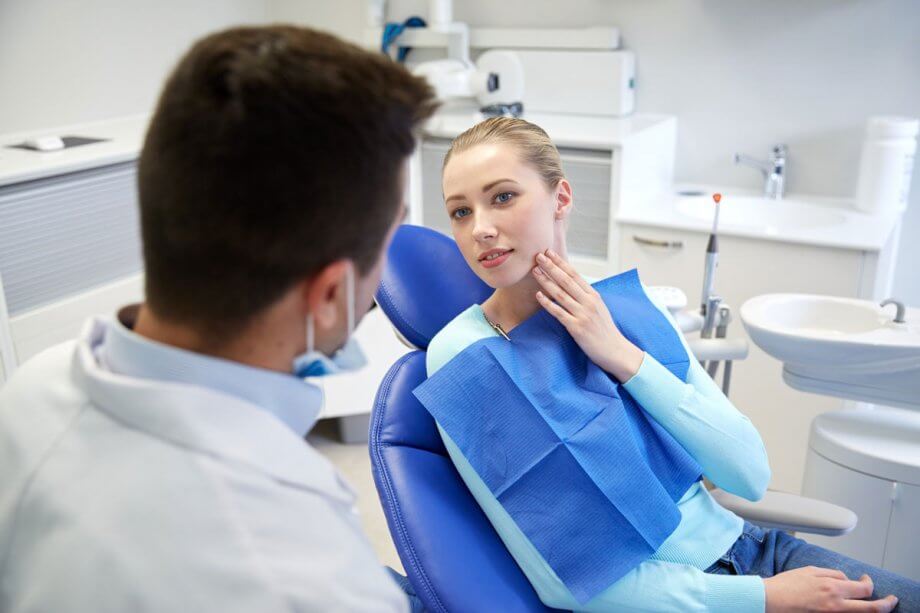 young woman in exam chair talking with dentist